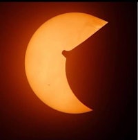 a solar eclipse with a crescent moon in the background